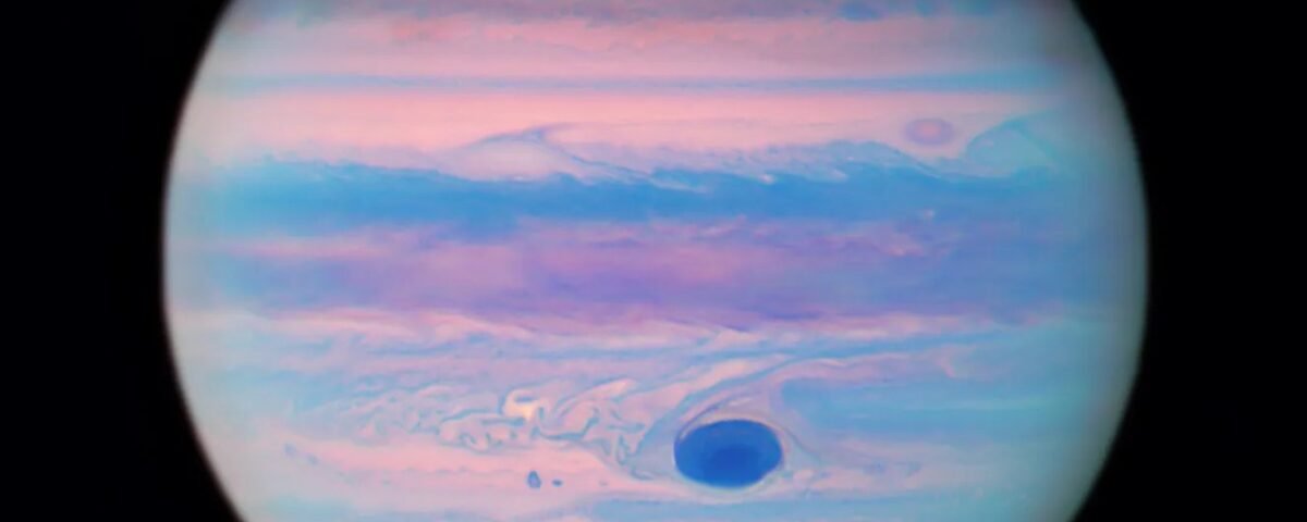 Jupiter looks iridescent in this ultraviolet image from the Hubble Space Telescope. The poles are a muted orange color, while swirls and stripes of pink, orange, blue, and purple cover the rest of the planet. Jupiter's "Great Red Spot" appears a deep blue here.